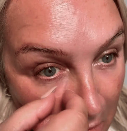 Close-up of a person's eye with a hand touching the eyelid