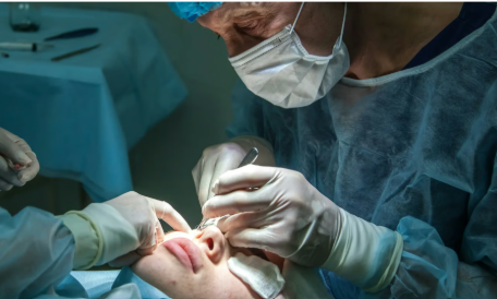 Medical procedure being performed with surgical tools and gloves on a patient.